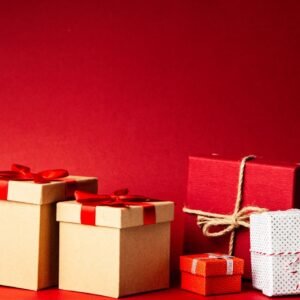 A collection of colorful gift boxes with ribbons on a rich red background, perfect for holiday themes.